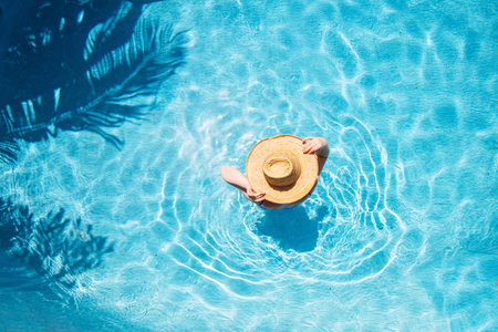 Top view of beautiful woman earing sunhat relaxing in swimming pool