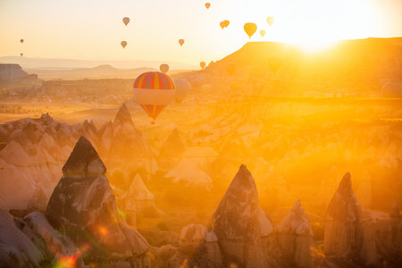 Gorgeous sunrise scenery of hot air balloons flying over Love valley with rock formations and fairy chimneys in Cappadocia Turkeyの写真素材