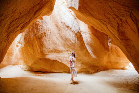 Young woman in cave with sunbeams shining down through ceilingの写真素材