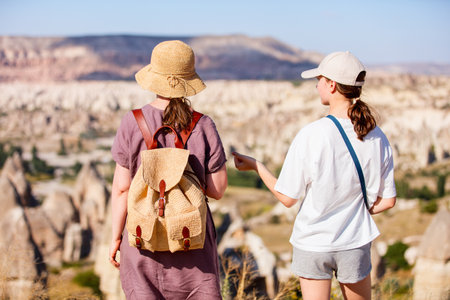 Back view of mother and daughter family enjoying view of valley with rock formations and fairy chimneys in Cappadocia Turkeyの写真素材