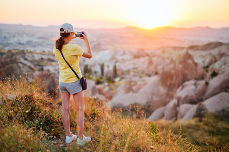 Teenage girl enjoying stunning sunset while hiking in Red valley in Cappadocia Turkey among beautiful rock formationsの写真素材
