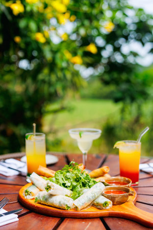Traditional vietnamese rolls served with other small bites with tropical cocktailsの写真素材
