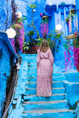 Back view of young woman exploring bright blue streets of the Blue City of Jodhpur in Indiaの写真素材