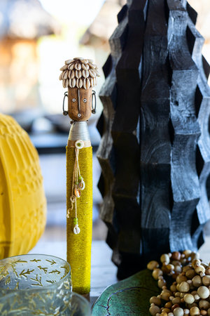 A handcrafted African tribal figurine adorned with beads, cowrie shells, and intricate detailing, surrounded by traditional home decor elements, showcasing cultural artistry and heritage.の写真素材
