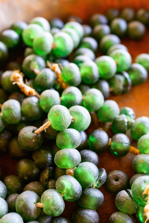 Close-up of vibrant green African glass beads, tied together with natural fiber, showcasing traditional craftsmanship and cultural artistry, often used in jewelry and decorative items.の写真素材