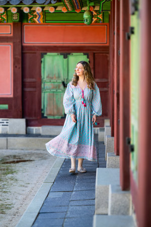 A tourist woman in colorful dress explores the vibrant, intricately decorated interior of a traditional Korean temple in Seoul, South Korea.の写真素材