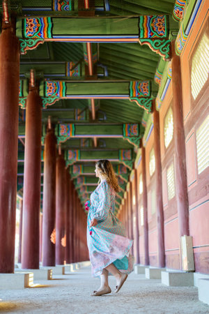 A tourist woman in colorful attire explores the vibrant, intricately decorated interior of a traditional Korean temple in Seoul, South Korea.の写真素材