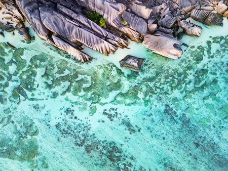 An aerial view of Anse Source d&#39;Argent&#39;s granite rock formations and shallow, turquoise waters with visible reef patterns on La Digue, Seychellesの写真素材