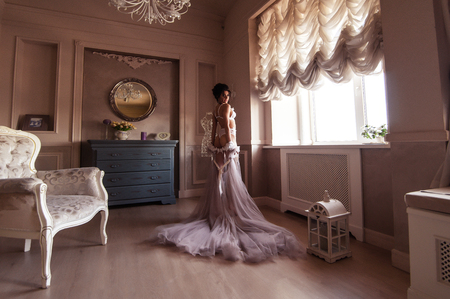 Boudoir morning of the bride. Bride stay near the windowの写真素材