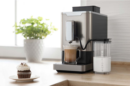 Coffee machine makes cappuccino with cupcake on the kitchenの写真素材