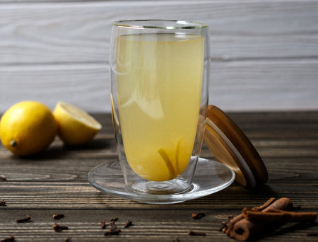 Hot drink with lemon in a transparent glass with a double bottom on wooden tableの写真素材