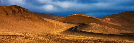 Curved desert road leading between hills in Icelandの写真素材
