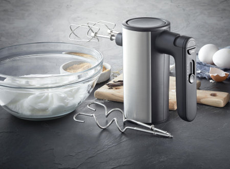 Electric hand mixer with whipped cream on kitchen tableの写真素材
