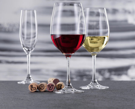 Red and white wine glasses with cork on a tableの写真素材