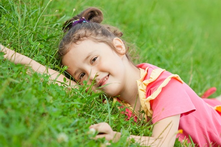 The little girl lies on a green grass a close upの写真素材