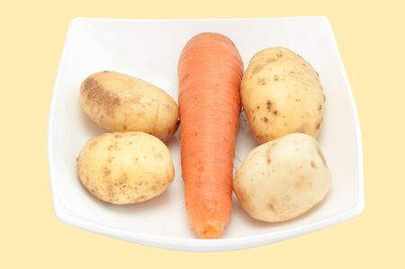 Carrots and potato on a white plate close up it is isolatedの写真素材