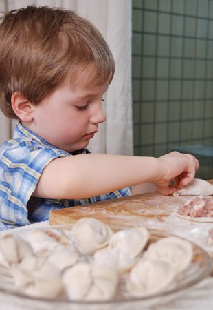 little boy preparing russian meat dumplingsの写真素材