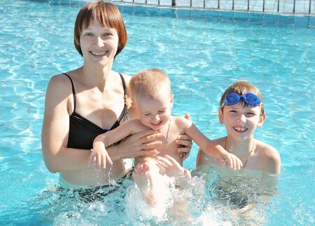 mother playing with her sons in the water poolの写真素材