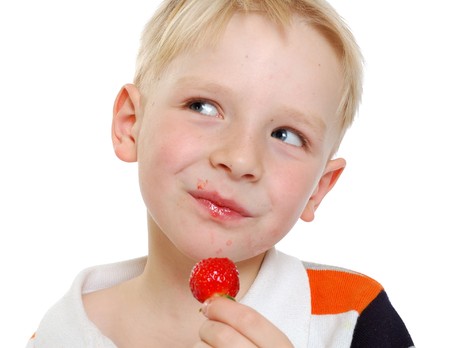 little cute boy eat strawberries in a white backgroundの写真素材