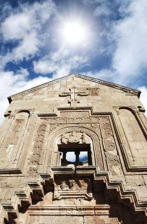 the facade of old medieval church against cloudy sunny  sky background