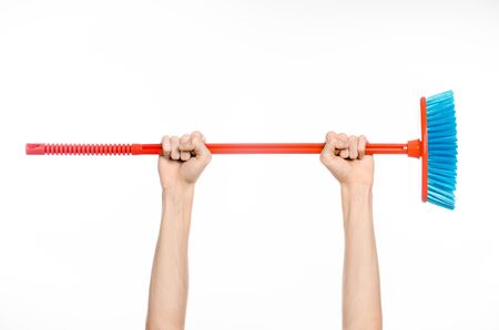 Cleaning the house topic: human hand holding a red broom isolated on a white backgroundの写真素材