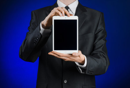 Presentation and business theme: a man in a black suit holding a white tablet touch computer gadget...