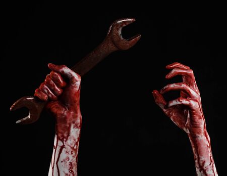 bloody hand holding a big wrench, bloody wrench, big key, bloody theme, halloween theme, crazy mechanic, murderer, psycho, violence, zombies, black background, isolated, revolution studioの写真素材
