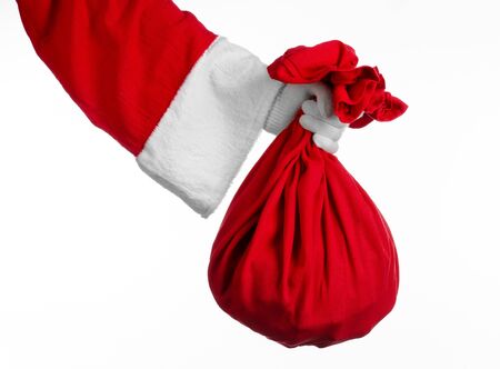 Santa Claus theme: Santa holding a big red sack with gifts on a white background studioの写真素材