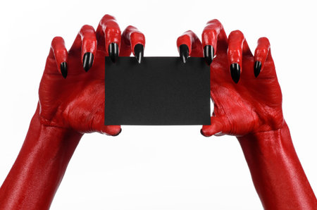 Halloween theme: Red devil hand with black nails holding a blank black card on a white background...