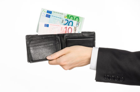 Money and business topic: hand in a black suit holding a wallet with banknotes 10,20 and 100 euro on...