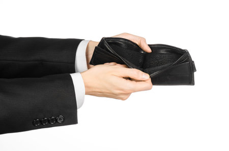 Poverty and money theme: a man in a black suit holding a empty purse isolated on white background
