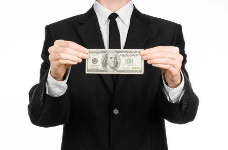 Money and business theme: a man in a black suit holding a bill of 100 dollars and features a hand...