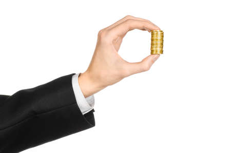 Money and business topic: hand in a black suit holding a pile of gold coins in the studio on a white backgroundの写真素材