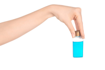 Beauty and health topic: a woman's hand holding a small blue bottle of shampoo in the studio...