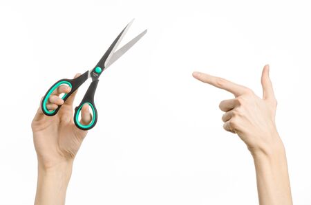 Office and home topic: human hand holding a black scissors with blue accents on a white isolated backgroundの写真素材
