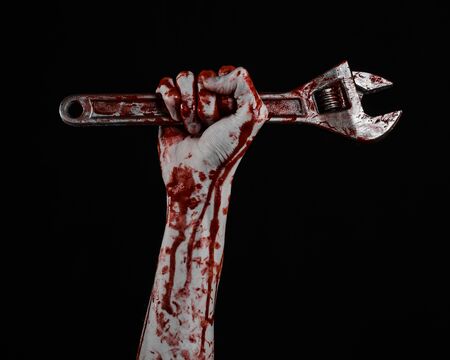 Halloween theme: bloody hand holding a big wrench on a black background studioの写真素材