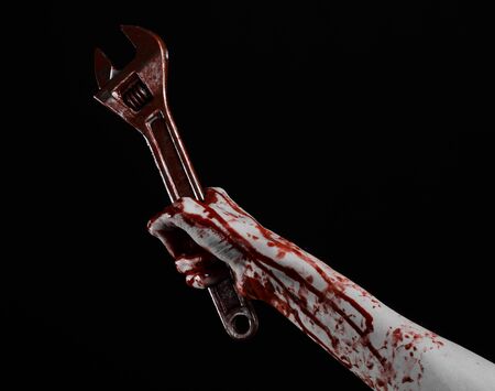 Halloween theme: bloody hand holding a big wrench on a black background studioの写真素材