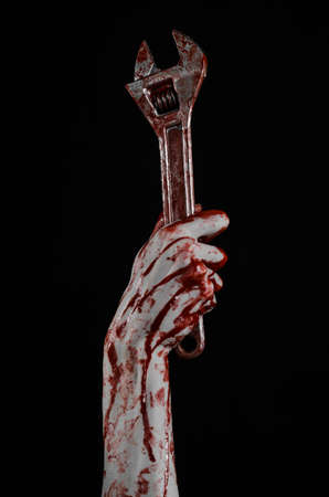 Halloween theme: bloody hand holding a big wrench on a black background studioの写真素材