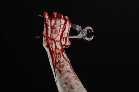 Halloween theme: bloody hand holding a pliers on a black background studioの写真素材