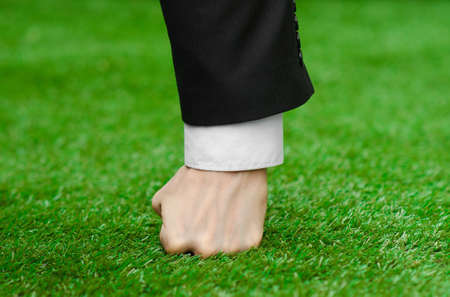 Nature and business topic: the hand of man in a black suit presses his fist green grass studioの写真素材