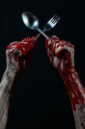 bloody hand holding a spoon, fork, halloween theme, bloody spoon, fork, black background, isolated...