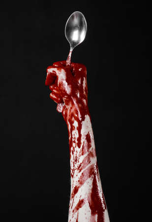 bloody hand holding a spoon, fork, halloween theme, bloody spoon, fork, black background, isolated studioの写真素材