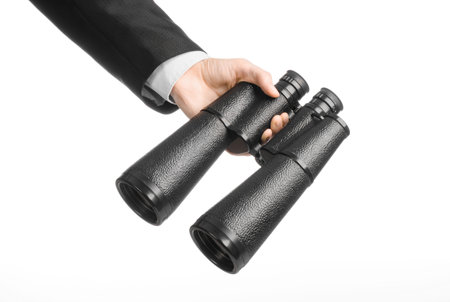 Business and search topic: Man in black suit holding a black binoculars in hand on white isolated backgroundの写真素材