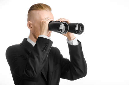 Business and search topic: Man in black suit holding a black binoculars in hand on white isolated backgroundの写真素材