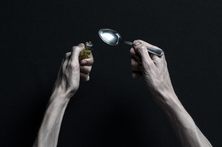 The fight against drugs and drug addiction topic: hand addict lies on a dark table and around it are drugsの写真素材