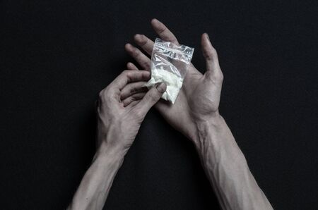 The fight against drugs and drug addiction topic: hand addict lies on a dark table and around it are drugsの写真素材