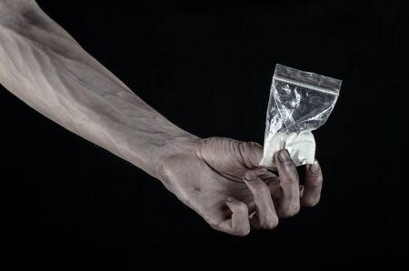 The fight against drugs and drug addiction topic: dirty hand holding a bag addict cocaine on a black backgroundの写真素材