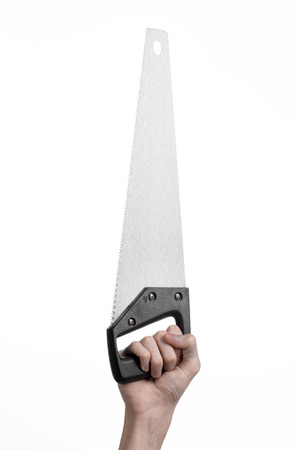 Construction topic: hand holding a saw with a black pen on a white background isolatedの写真素材