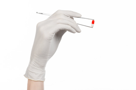 Pharmacology and Medical theme: doctor's hand in a white glove holding tweezers with red pill capsule isolated on white background in studioの写真素材