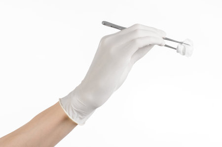 Medicine and Surgery theme: doctor's hand in a white glove holding tweezers with swab isolated on white background in studioの写真素材